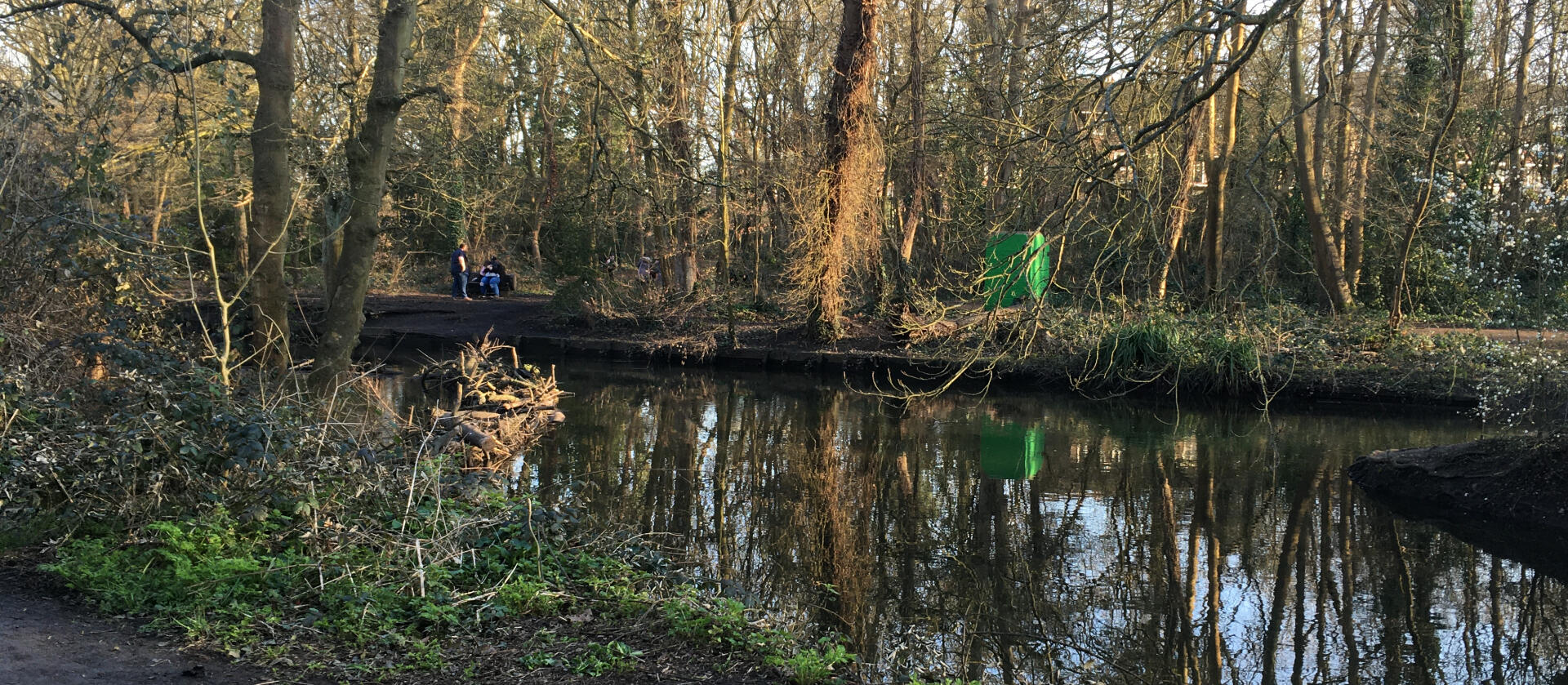 view across water to far bank of river where small group of people are gathered (indistinct)